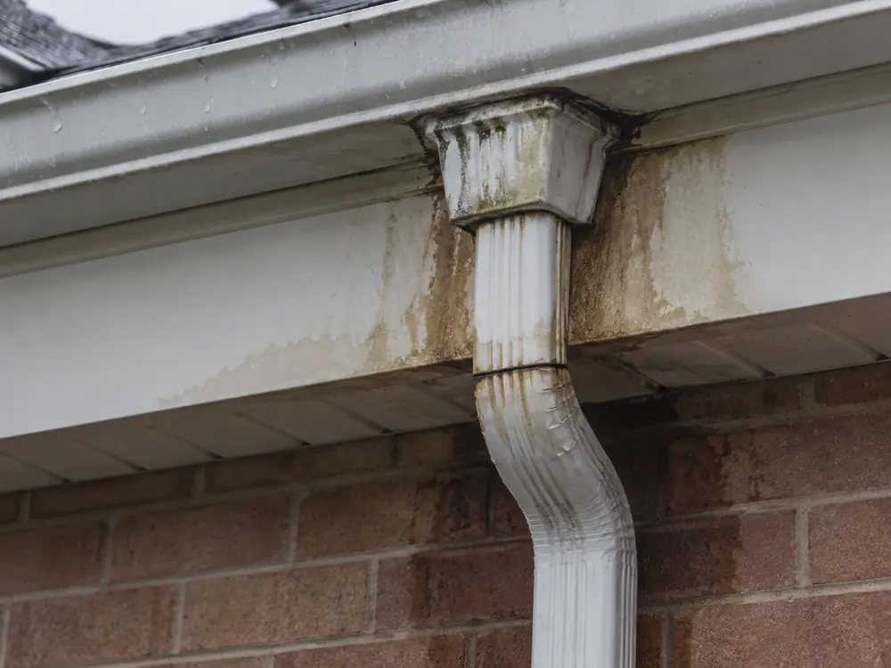 Damaged eavestrough outlet with water staining