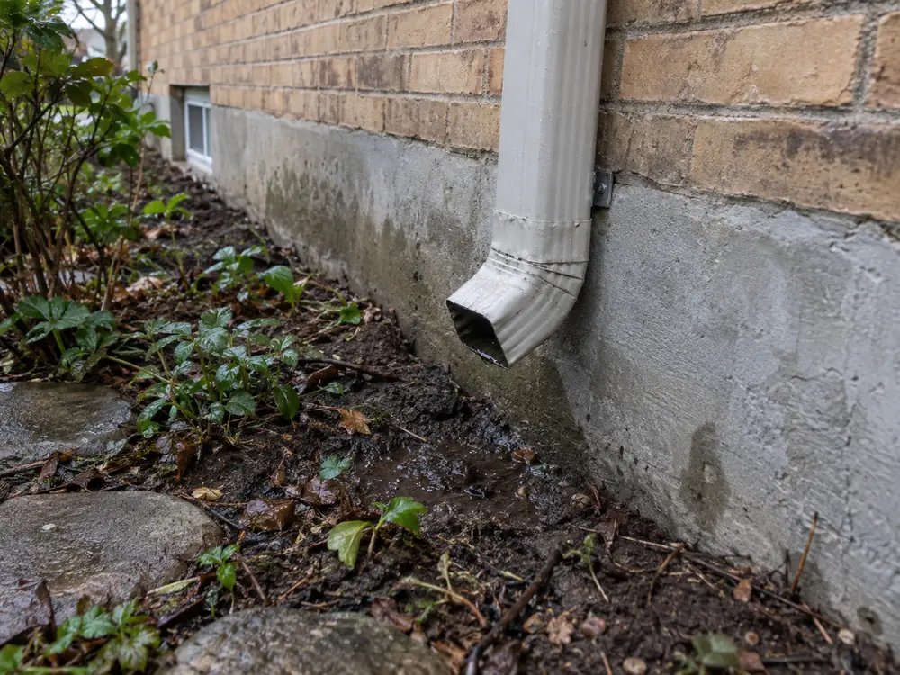 Downspout ending beside a residential foundation