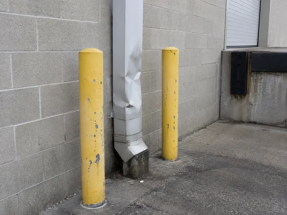 Commercial exterior downspout being assessed beside a Mississauga loading area